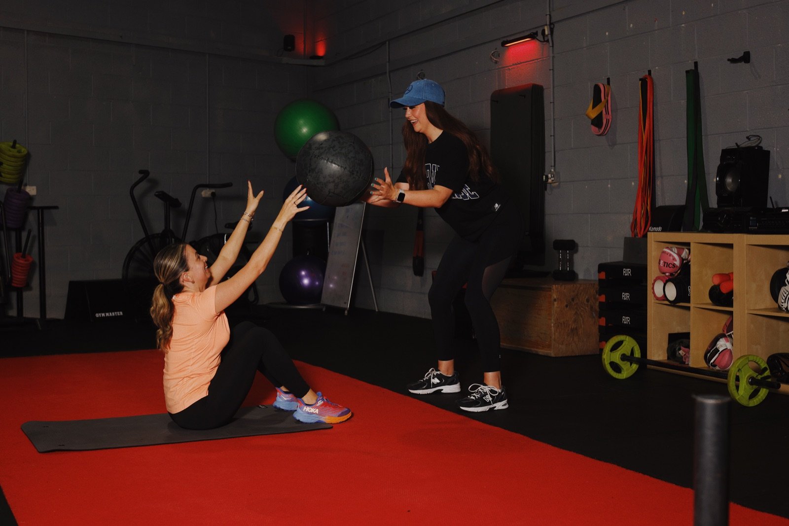 A GymSpace coach guiding a member through a medicine-ball exercise