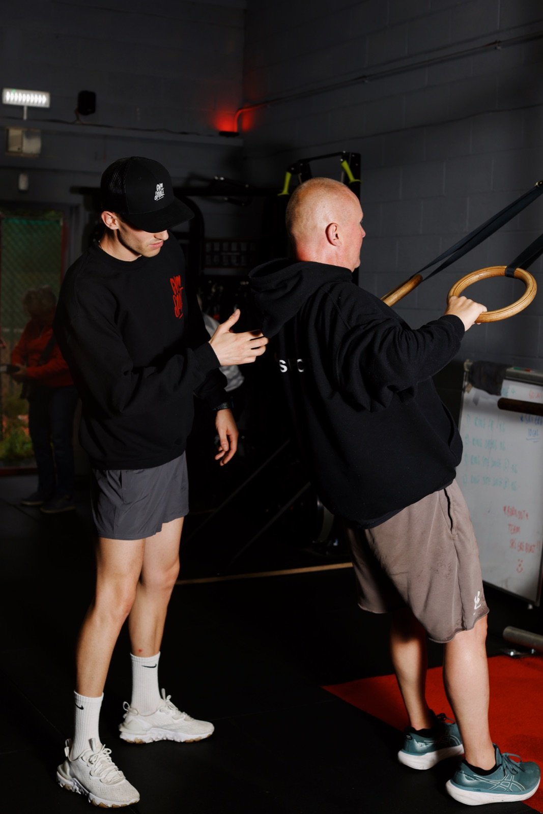 A GymSpace coach supporting a member using gymnastic rings