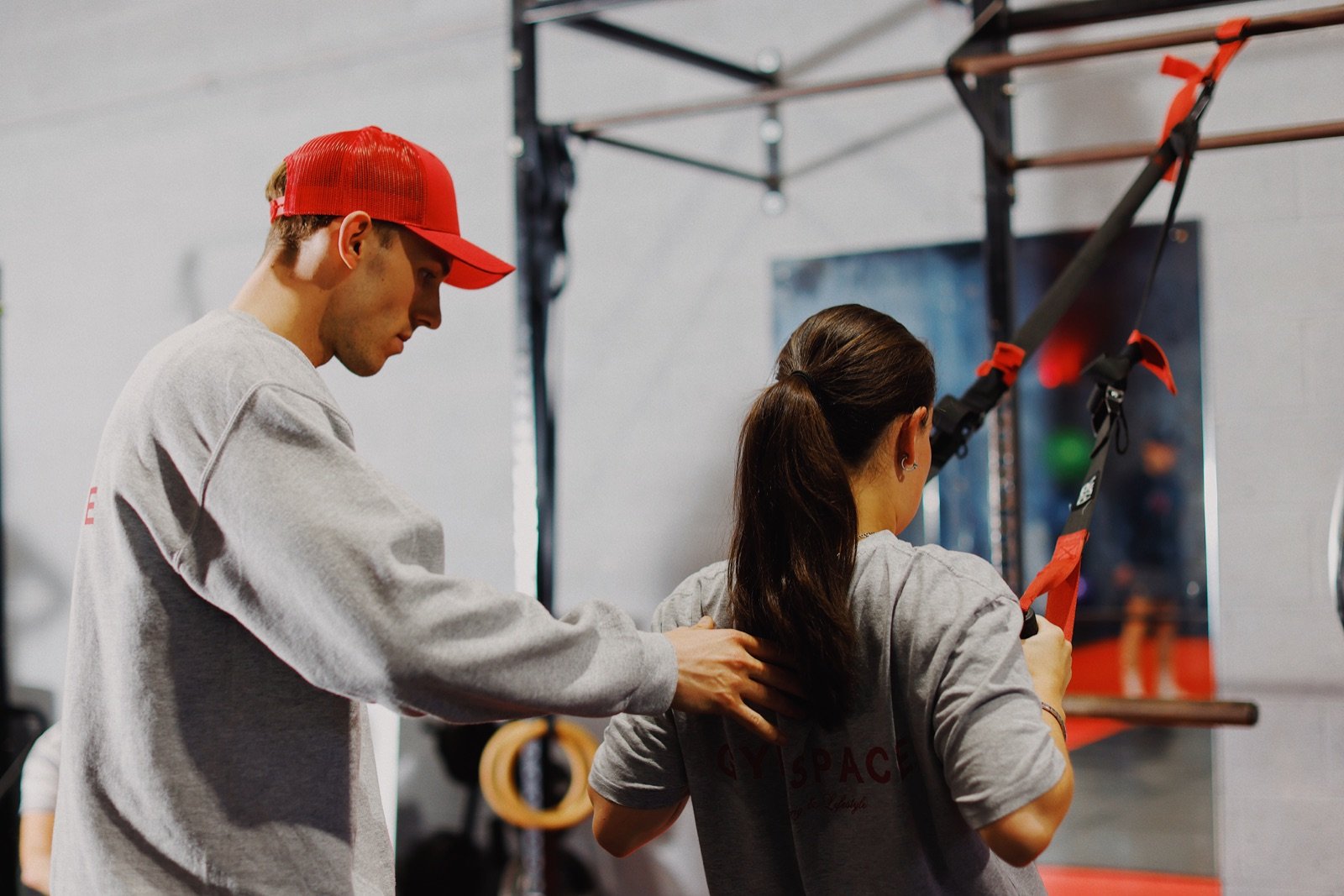 A GymSpace coach helping a member with suspension training
