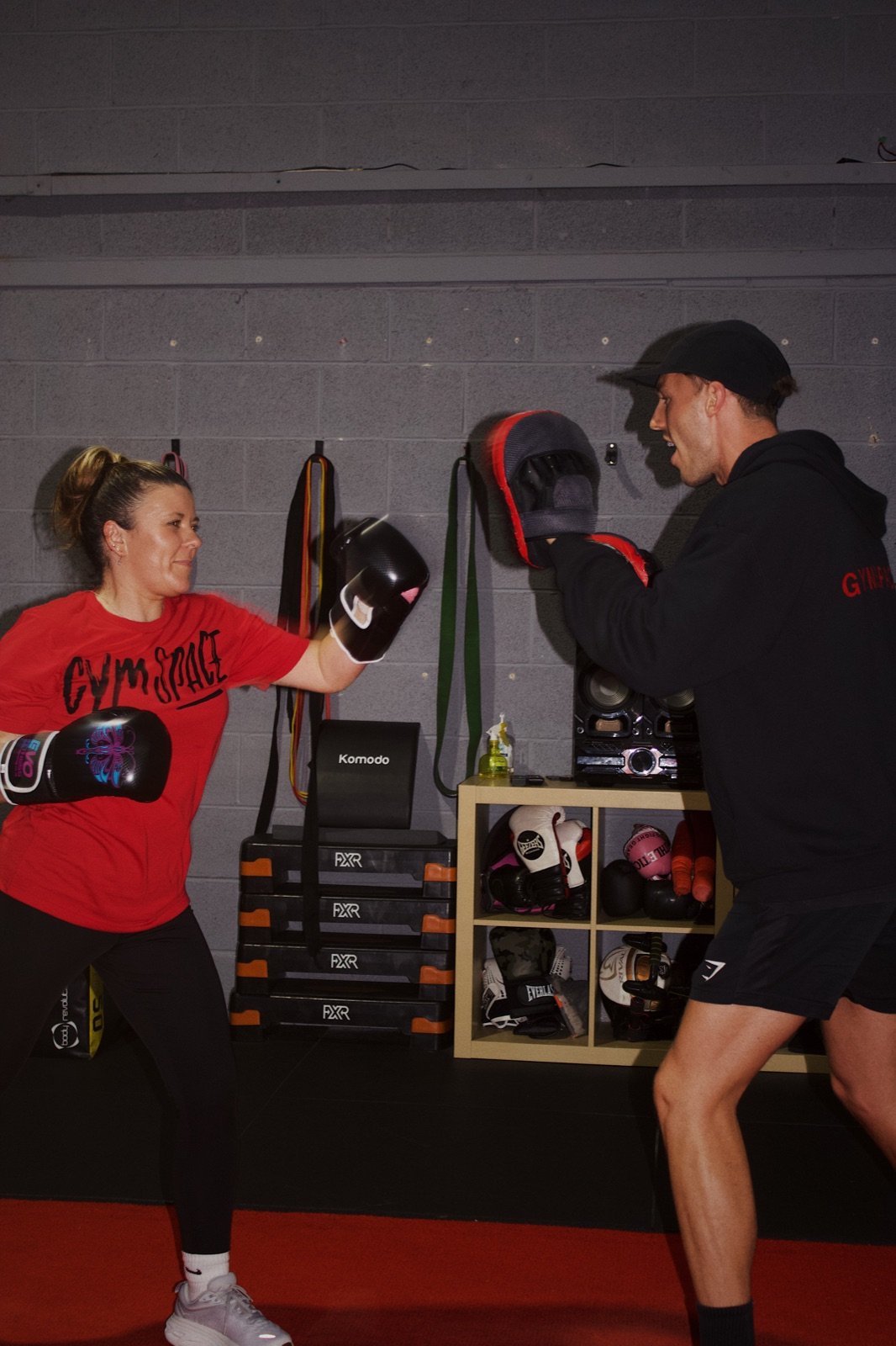 A GymSpace coach guiding a member through boxing pad work