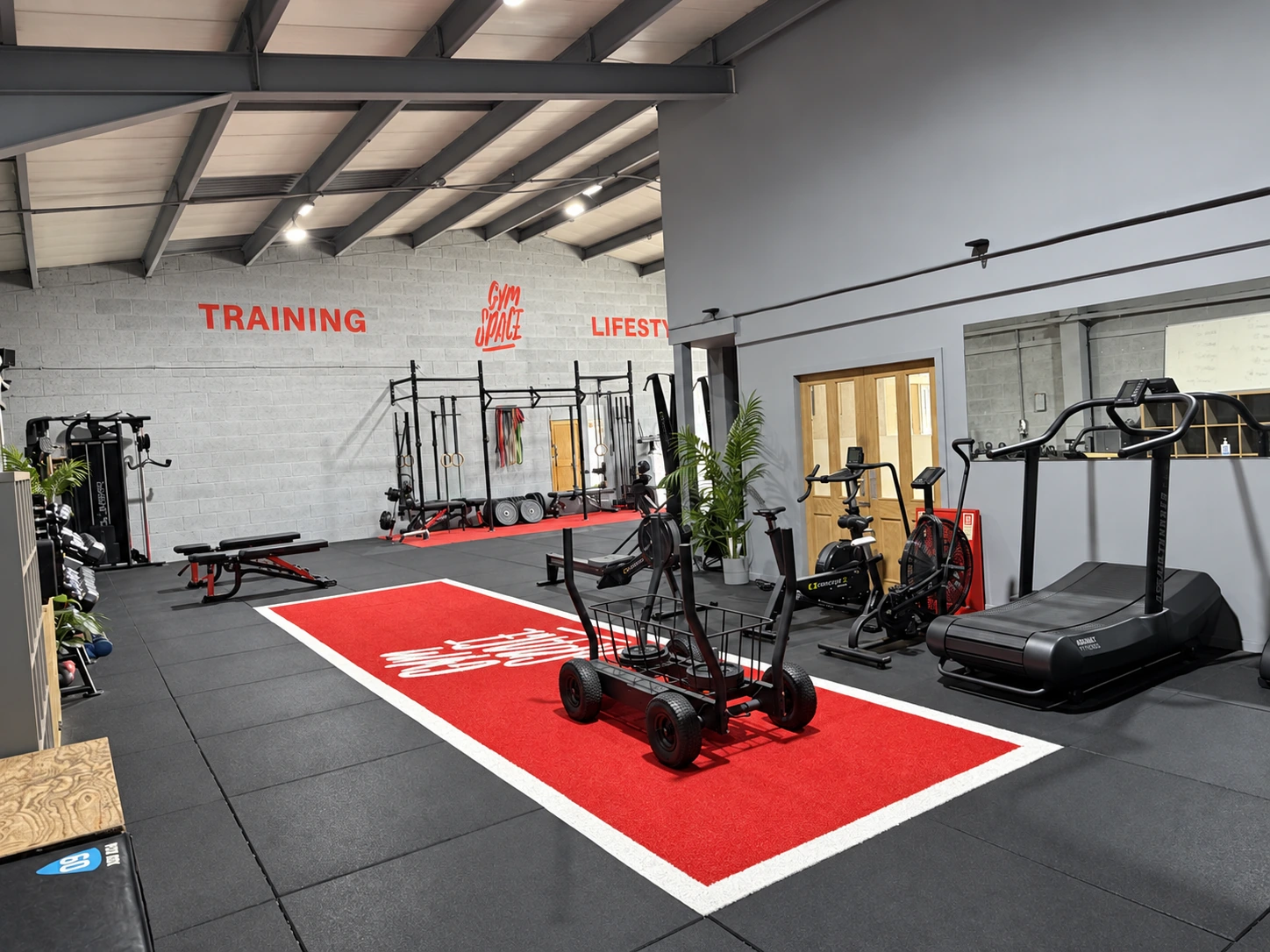 GymSpace training floor with red turf, sled and cardio equipment