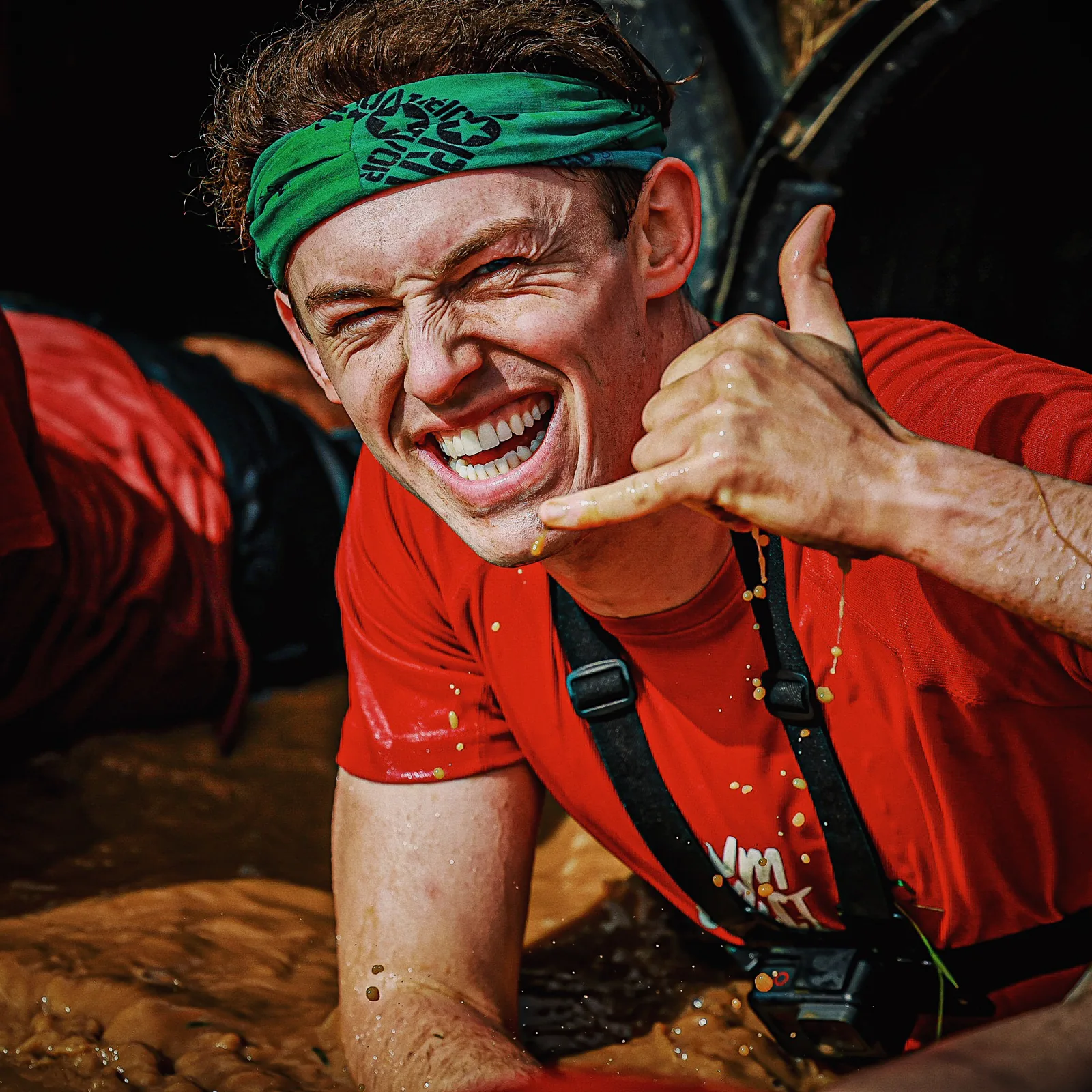 A GymSpace participant smiling during a muddy obstacle challenge