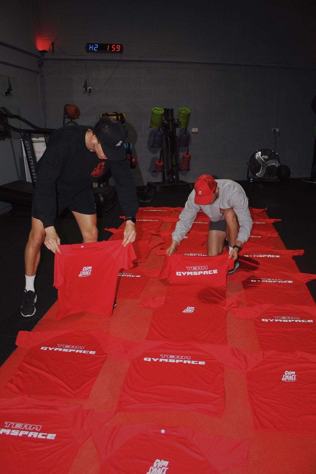 Coaches arranging red GymSpace T-shirts at the studio